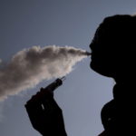 A woman exhales vapour from an e-cigarette outside the offices of British e-cigarette manufacturer Totally Wicked in Blackburn